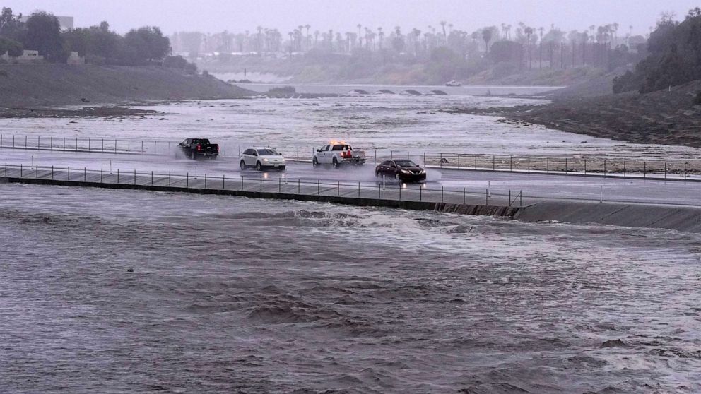 PHOTO: Vehicles cross over a flood control basin that has almost reached the street, Sunday, Aug. 20, 2023, in Palm Desert, Calif.