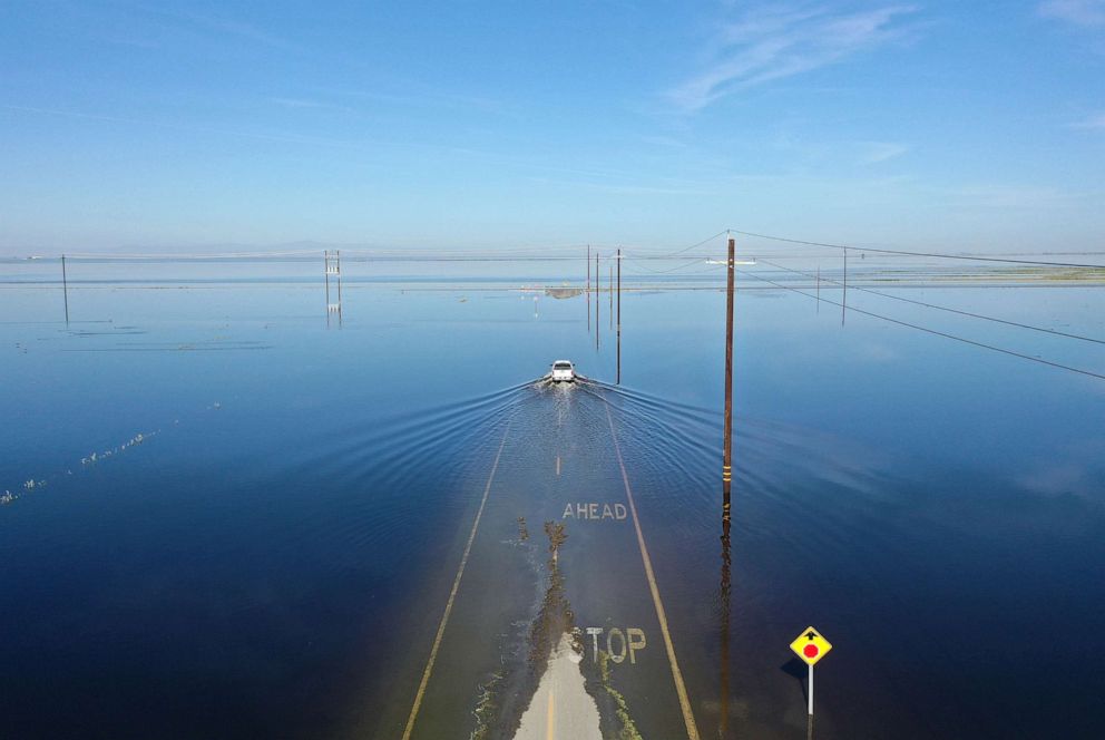 PHOTO: A vehicle drives through floodwaters in the reemerging Tulare Lake, in California's Central Valley, April 27, 2023, near Corcoran, Calif.