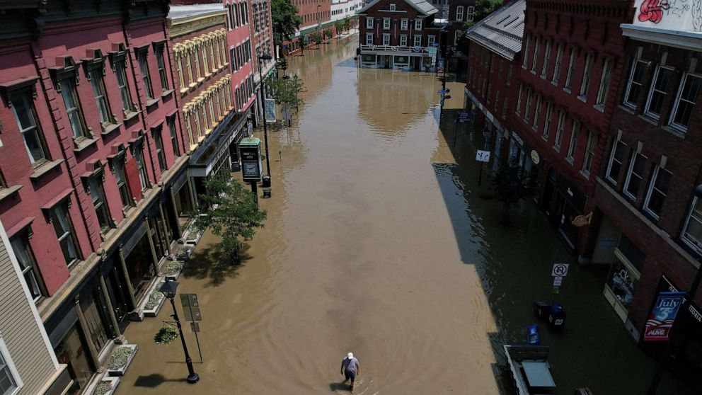 PHOTO: A man walks down a street flooded by recent rainstorms in Montpelier, Vermont, on July 11, 2023.