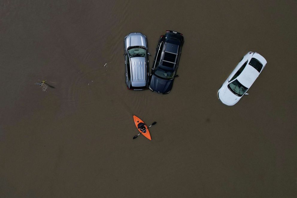 PHOTO: A person in a canoe passes parked cars partially submerged by floodwaters from recent rainstorms in Montpelier, Vermont, on July 11, 2023.