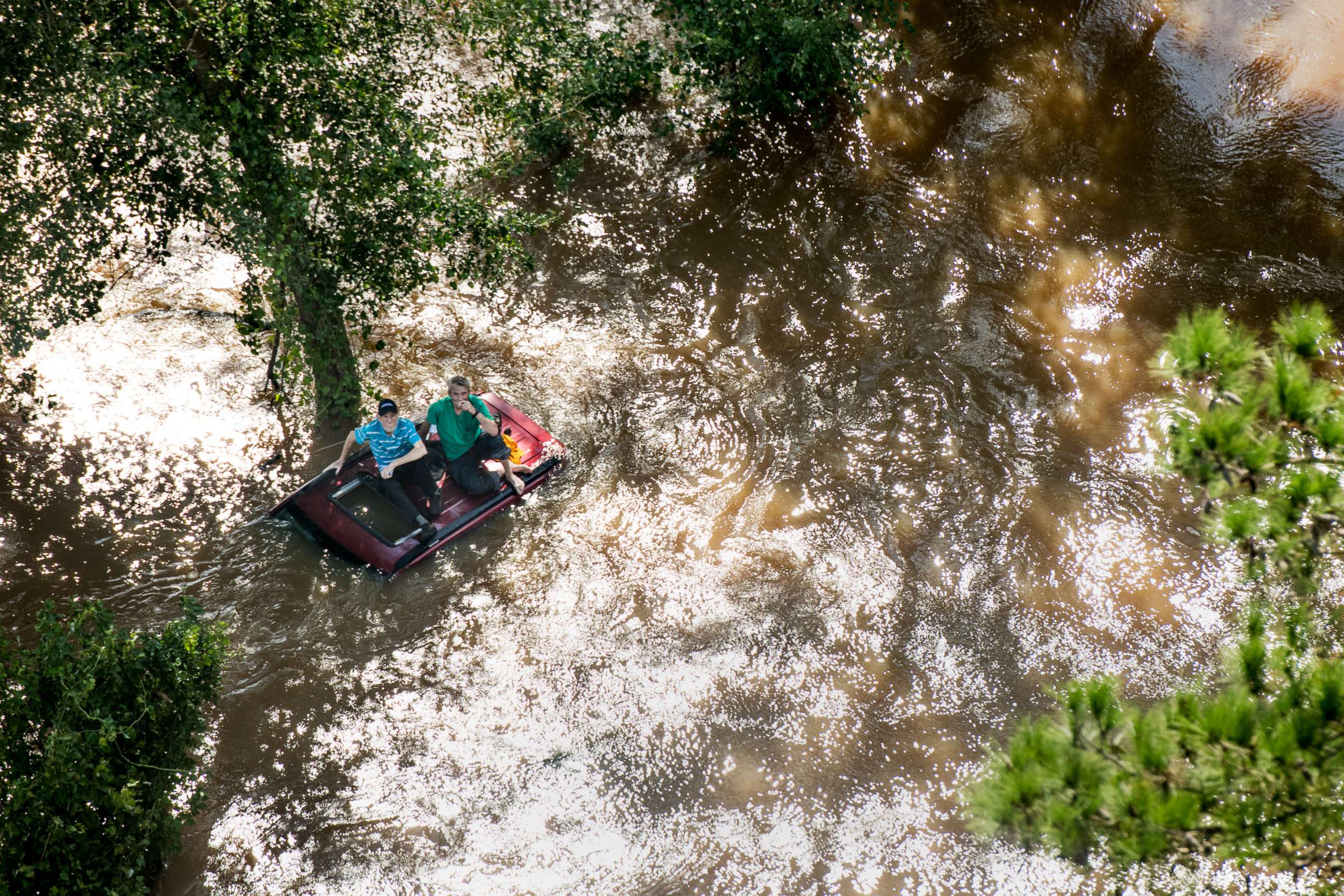 PHOTO: Two people sit on the roof of a vehicle trapped in floodwaters from Hurricane Florence, Sept. 17, 2018 in Wallace, S.C.