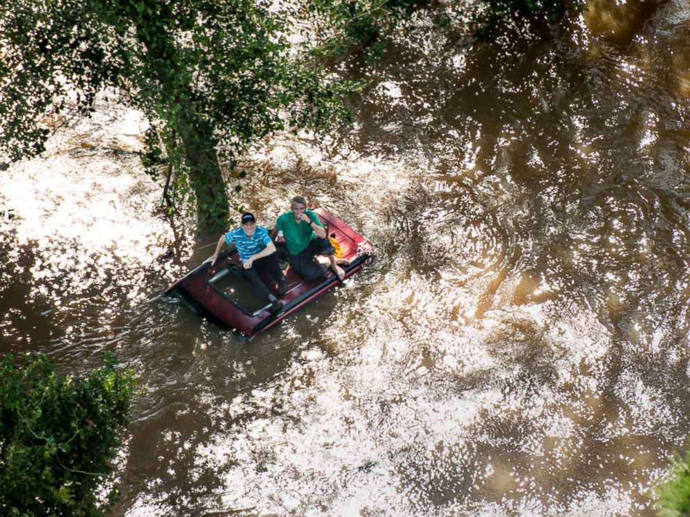 PHOTO: Two people are sitting on the roof of a car bomb in the waters of Hurricane Florence on September 17, 2018 in Wallace, S.C.