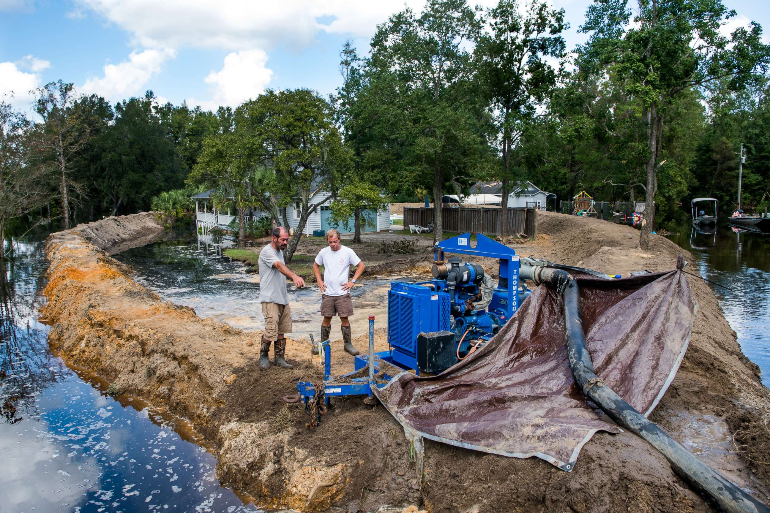 PHOTO: Jason Johnson, left, and homeowner Archie Sanders work to build a temporary levee to hold back floodwaters caused by Hurricane Florence near the Waccamaw River on Sept. 23, 2018 in Conway, S.C.