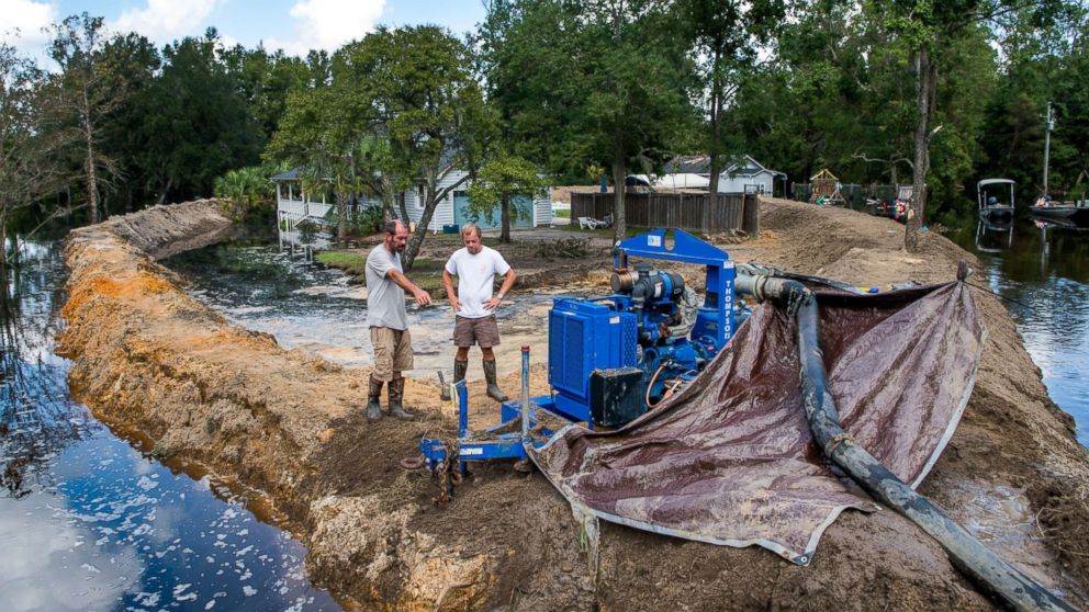 PHOTO: Jason Johnson, left, and homeowner Archie Sanders work to build a temporary levee to hold back floodwaters caused by Hurricane Florence near the Waccamaw River on Sept. 23, 2018 in Conway, S.C.