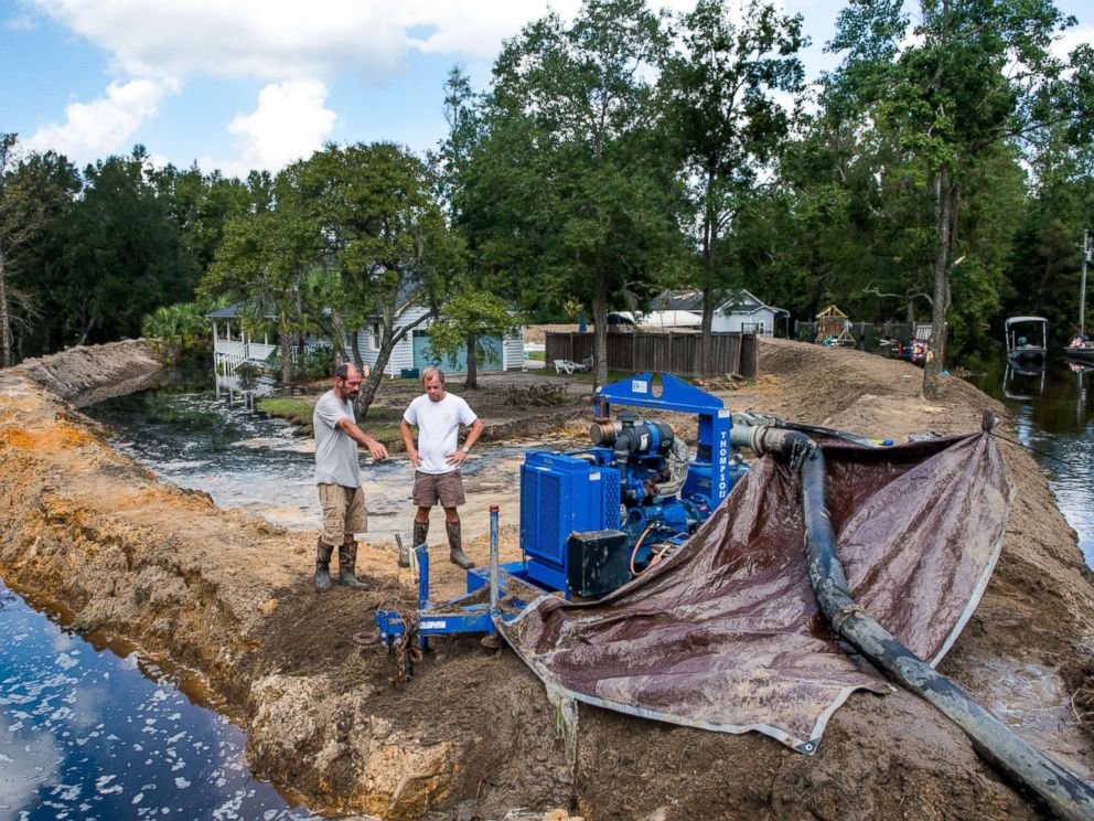 PHOTO: Jason Johnson, left, and homeowner Archie Sanders work to build a temporary levee to hold back floodwaters caused by Hurricane Florence near the Waccamaw River on Sept. 23, 2018 in Conway, S.C.