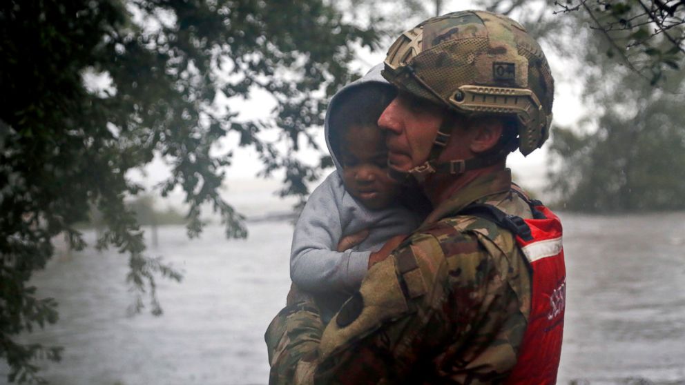 PHOTO: Rescue team member Sgt. Nick Muhar, from the North Carolina National Guard 1/120th battalion, evacuates a young child as the rising floodwaters from Hurricane Florence threatens his home in New Bern, N.C., on Friday, Sept. 14, 2018.