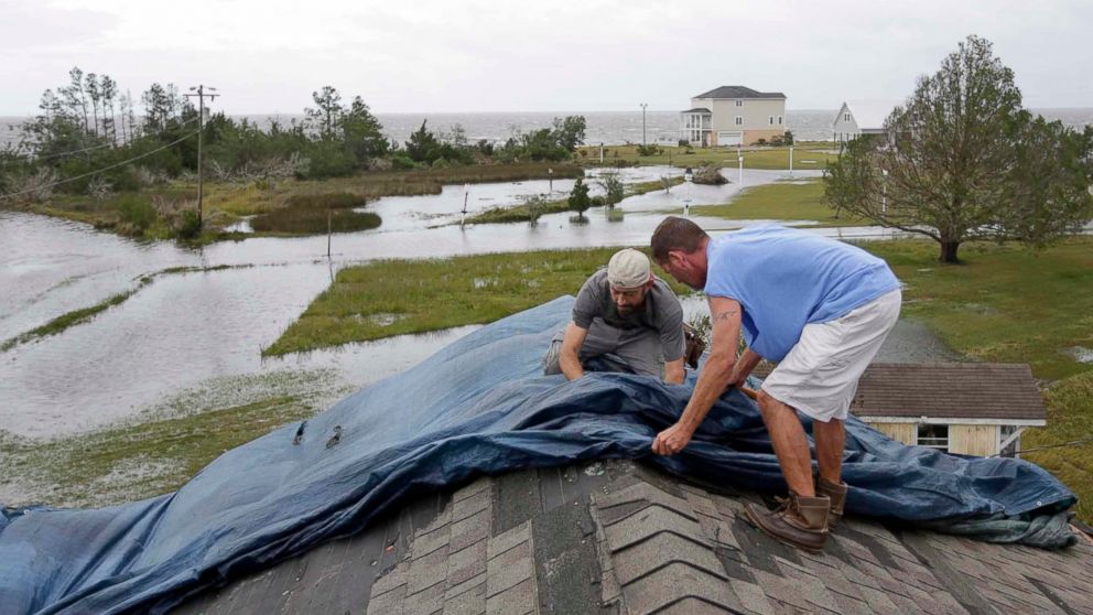 Jeff Pyron, left, and Daniel Lilly cover Lilly's roof after Hurricane Florence hit Davis N.C., Saturday, Sept. 15, 2018. The town had 4 1/2 feet of storm surge.