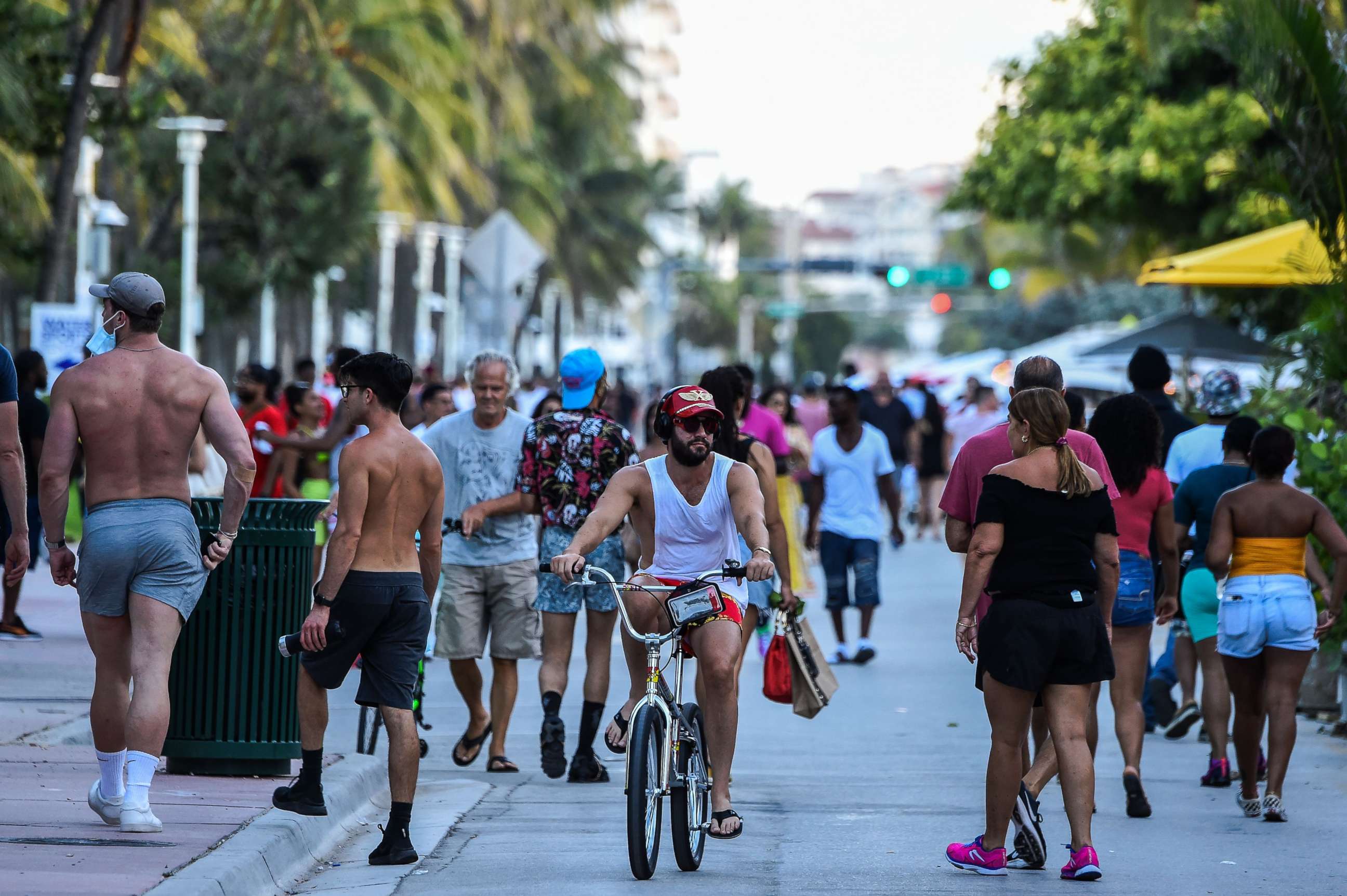 PHOTO: A man rides a bicycle as people walk on Ocean Drive in Miami Beach, Florida on June 26, 2020.
