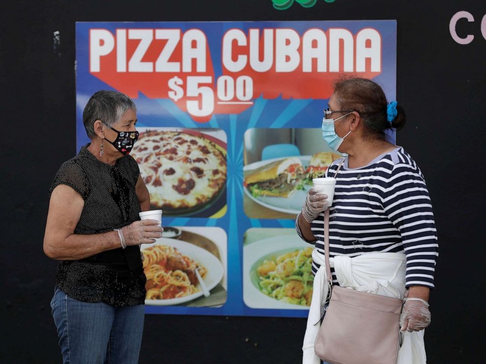 PHOTO: People, social distancing and wearing masks to prevent the spread of the new coronavirus, wait in line at a mask distribution event,June 26, 2020, in Miami. 