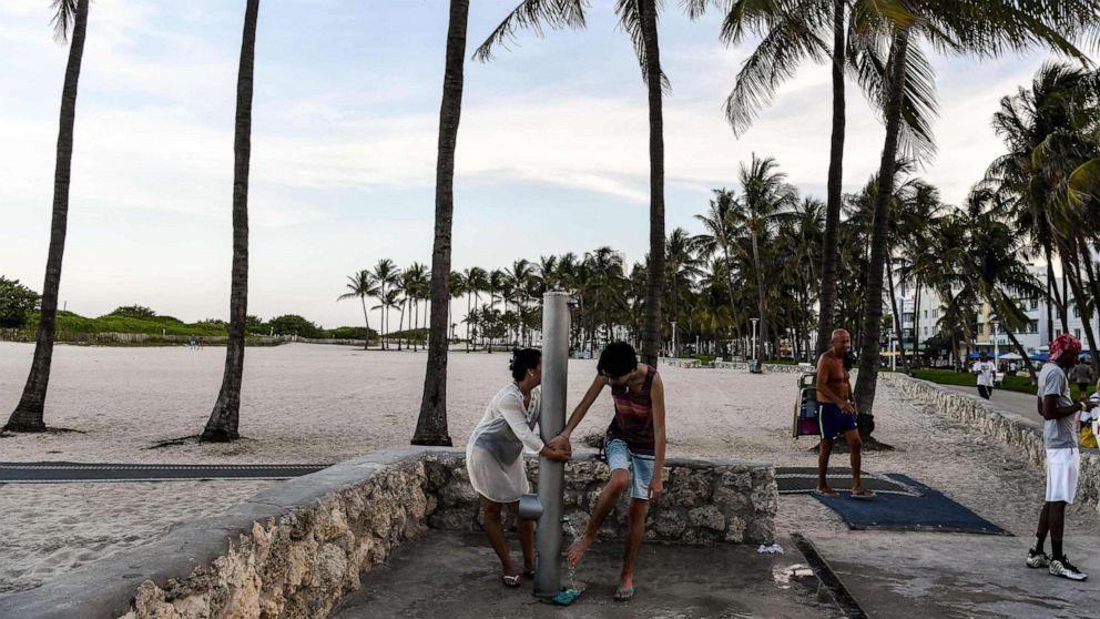 PHOTO: People rinse their feet in Miami, June 24, 2020. With coronavirus cases surging across the US South and West, officials are once again imposing tough measures, from stay-at-home advice in worst-hit states to quarantine.