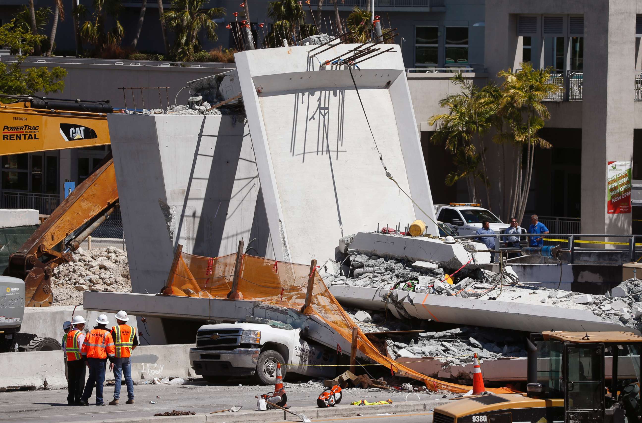PHOTO: Workers stand next to a section of a collapsed pedestrian bridge, Friday, March 16, 2018 near Florida International University in the Miami area.