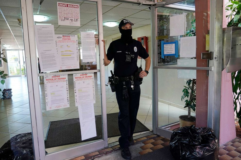 PHOTO: A Miami police officer stands at the entrance of a condominium building that was ordered evacuated, Aug. 10, 2021, in Miami.