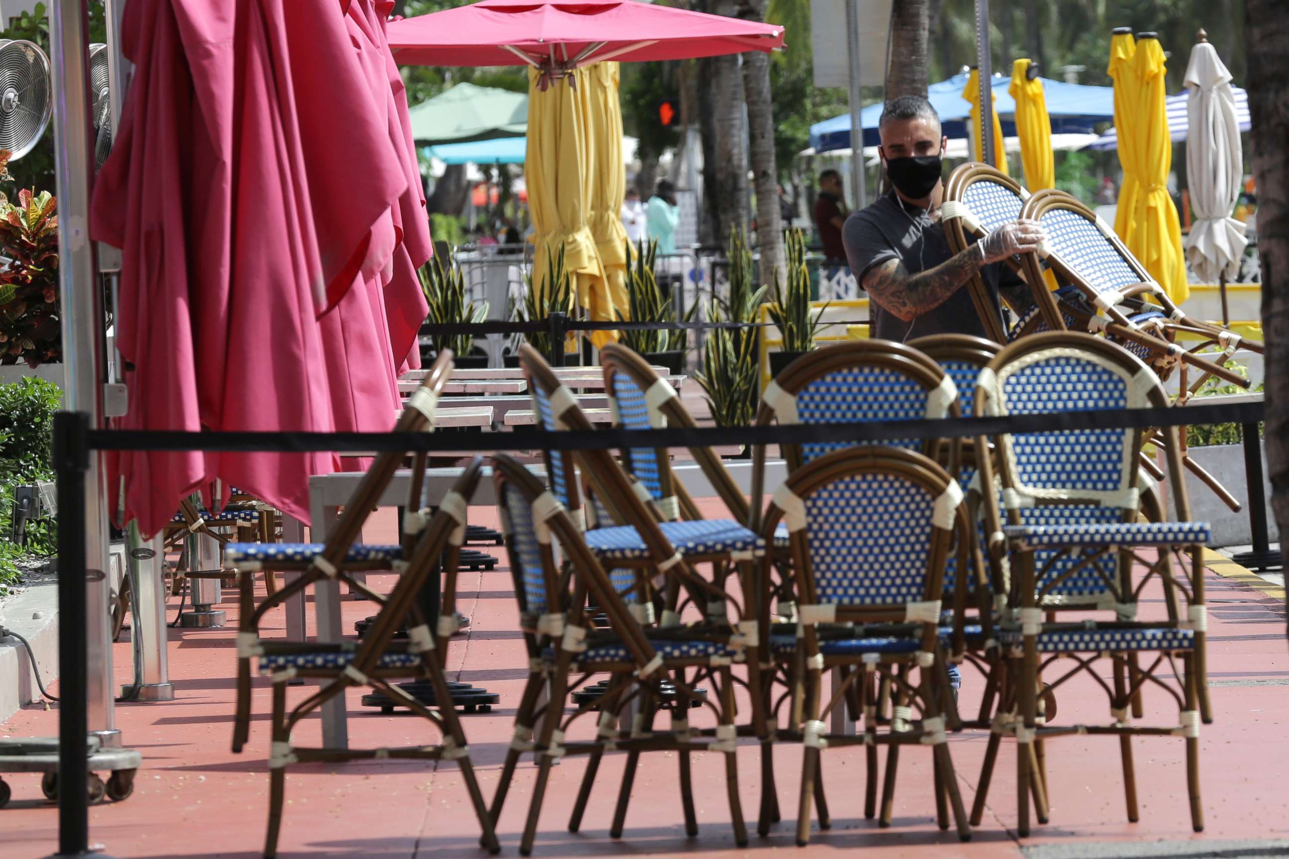 PHOTO: An employee at the Clevelander bar and restaurant on Ocean Drive stacks chairs as they have shut down due to public health concerns caused by COVID-19 during the coronavirus pandemic, July 13, 2020, in Miami Beach, Fla.