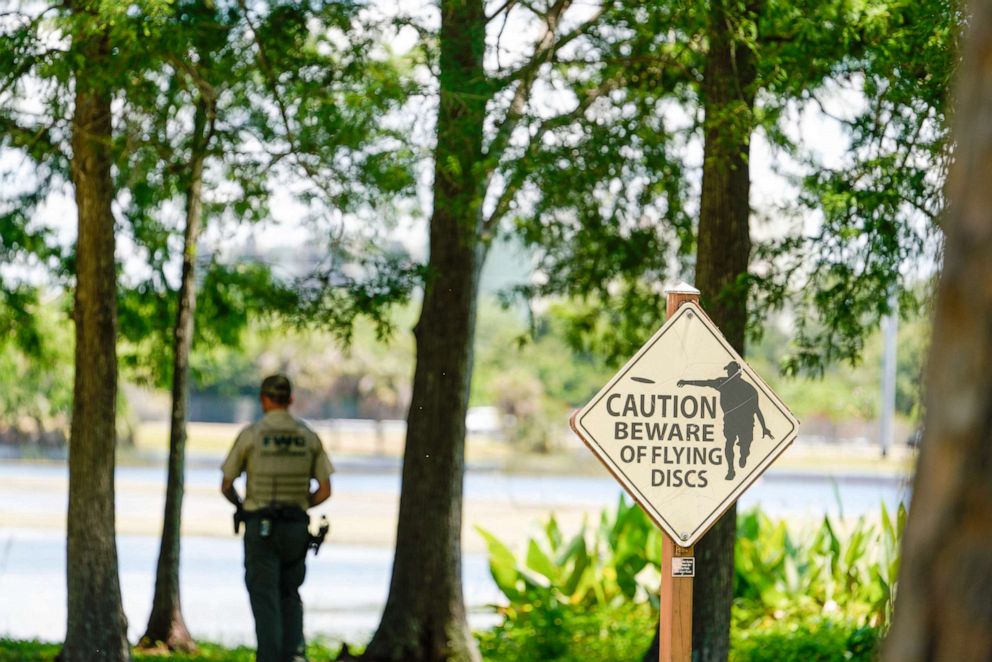 PHOTO: A Florida Fish and Wildlife Conservation Commission officers stands by a lake in John S. Taylor Park, where a man was found dead, May 31, 2022, in Largo, Fla.