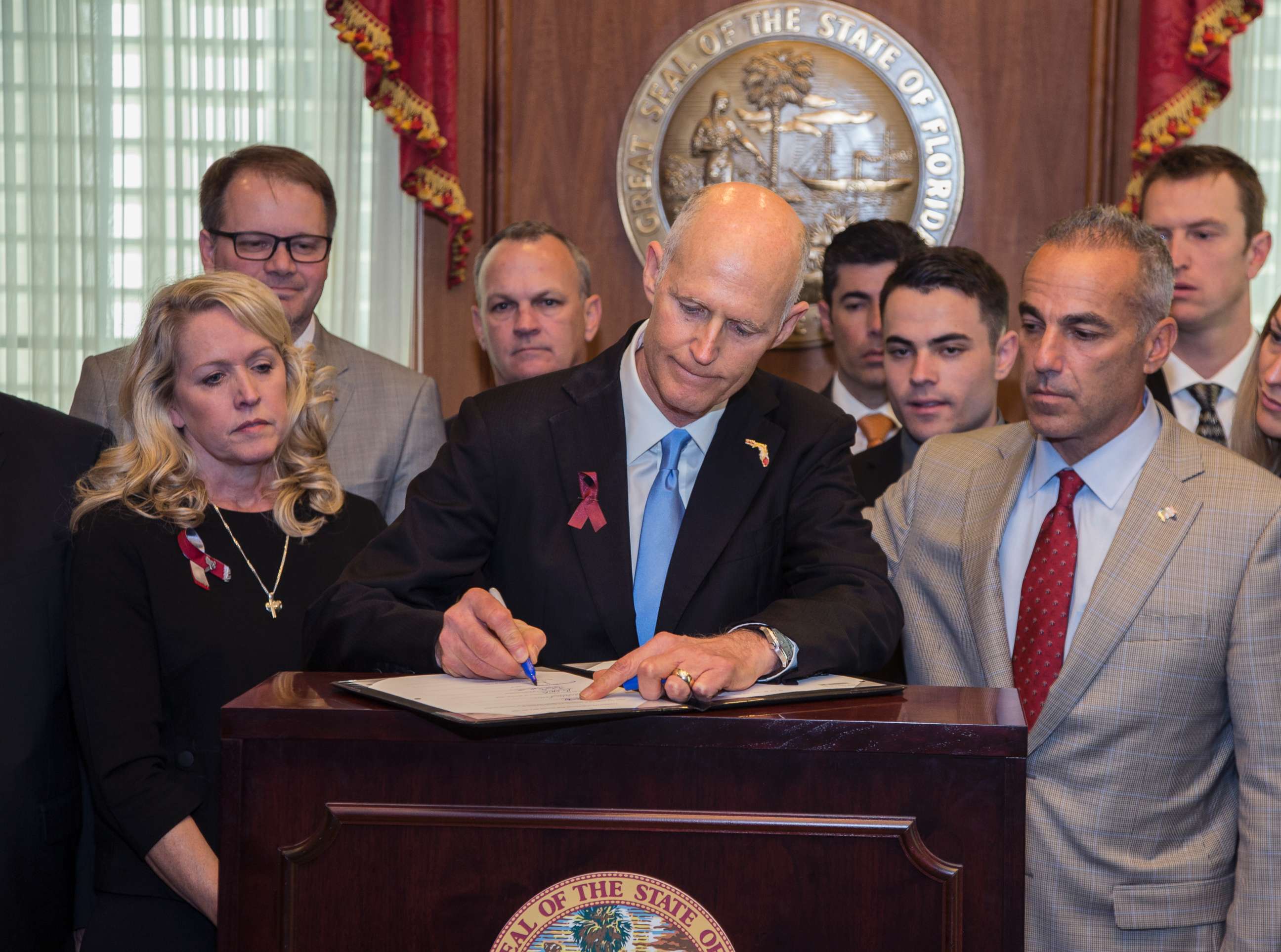 PHOTO: Florida Gov. Rick Scott signs the Marjory Stoneman Douglas Public Safety Act in the governor's office at the Florida State Capitol in Tallahassee, March 9, 2018. Scott is flanked by some of the parent's of the victims.