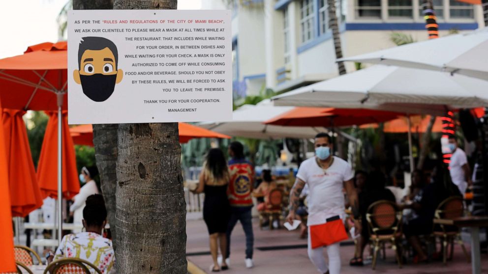 PHOTO: A sign informs customers at the Edison Hotel restaurant about wearing a protective face mask during the coronavirus pandemic, July 24, 2020, along Ocean Drive in Miami Beach, Fla.