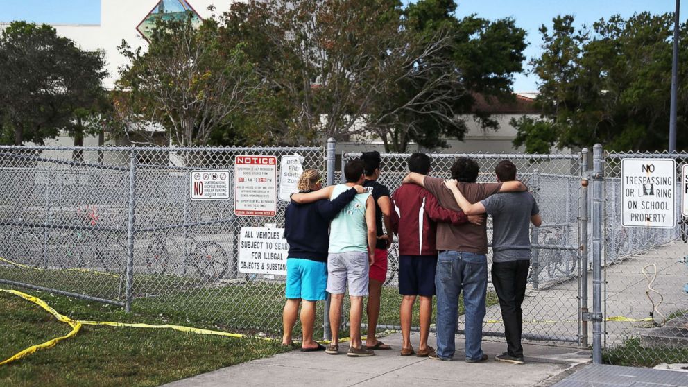 PHOTO: People look on at the Marjory Stoneman Douglas High School, Feb. 18, 2018, in Parkland, Florida.