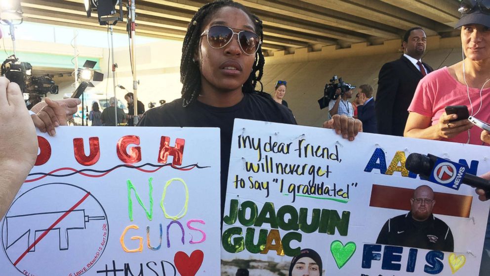 Tyra Hemans, a 19-year-old senior at Marjory Stoneman Douglas High School, sobs as she holds signs honoring slain teachers and friends near the police cordon around the school in Parkland Fla., Feb. 15, 2018.