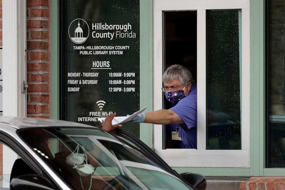PHOTO: Hillsborough County Library Service employee Stephen Duran wears a mask and gloves to protect himself from the coronavirus outbreak as he hands out unemployment paperwork, April 14, 2020, at the Jimmie B. Keel Regional Public Library in Tampa, Fla.