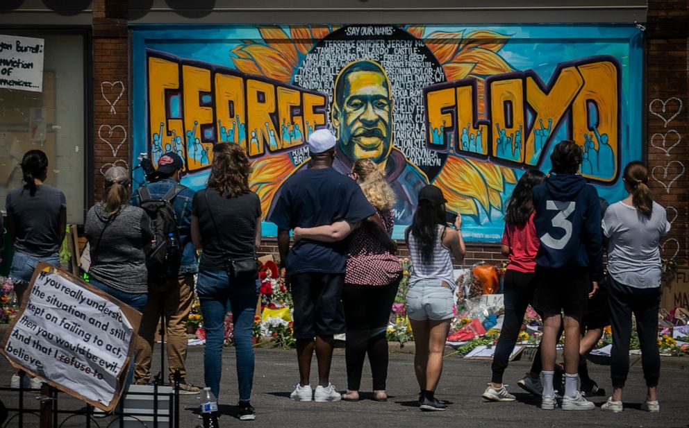 PHOTO: In this May 31, 2020 file photo, visitors make silent visits to organic memorial featuring a mural of George Floyd, near the spot where he died while in police custody, in Minneapolis, Minn.
