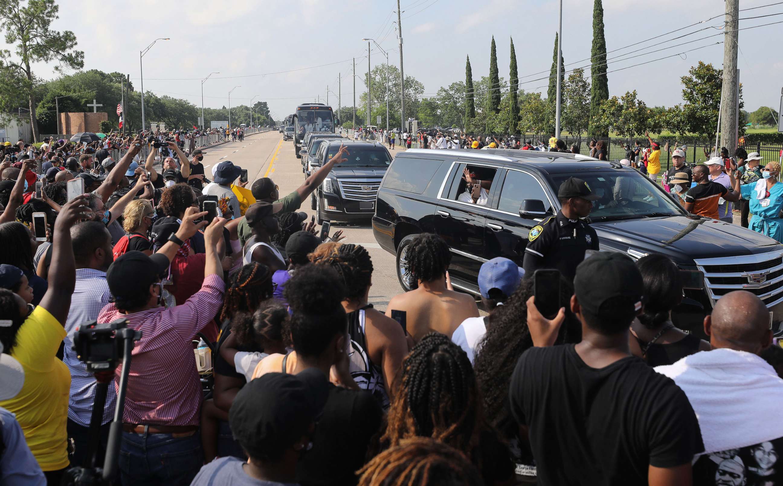PHOTO: Mourners in procession vehicles pass people in the street viewing the George Floyd funeral procession moments before entering Houston Memorial Gardens Cemetery for Floyd's burial, June 9, 2020, in Pearland, Texas. 