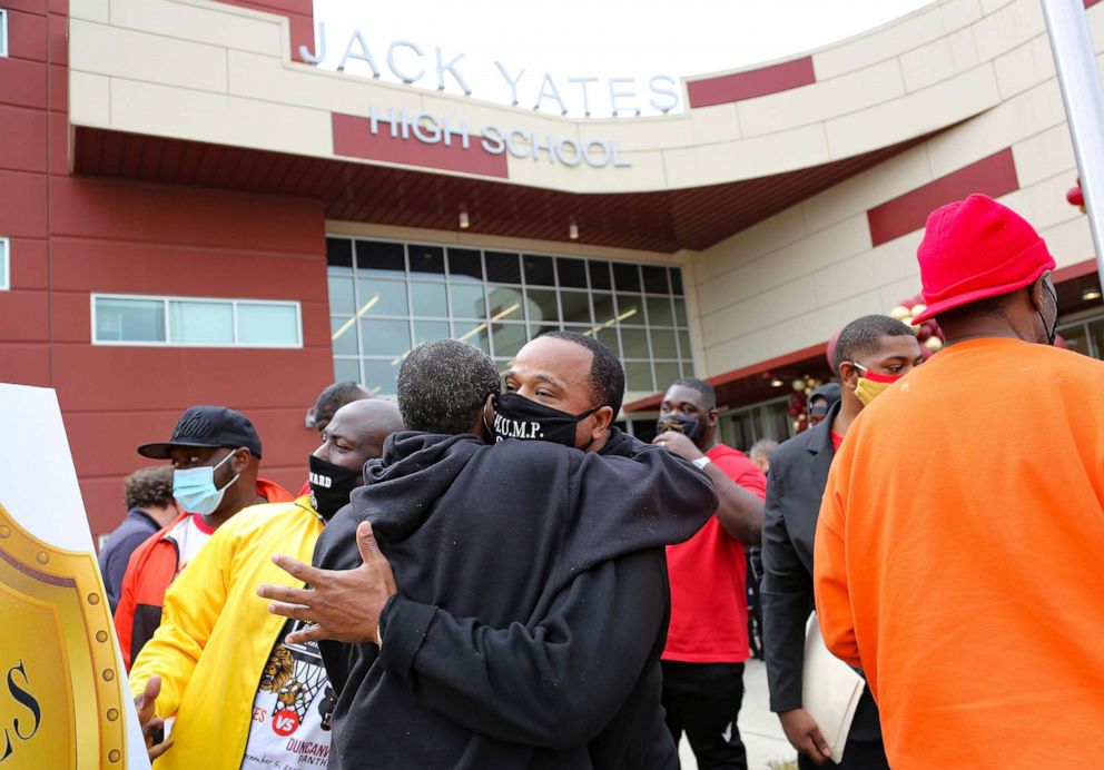PHOTO: Members of George Floyd's high school football team hug family members during a A Black History Month tribute to George Floyd and the Black Lives Matter movement at Jack Yates High School in Houston, Texas, Feb. 6, 2021. 