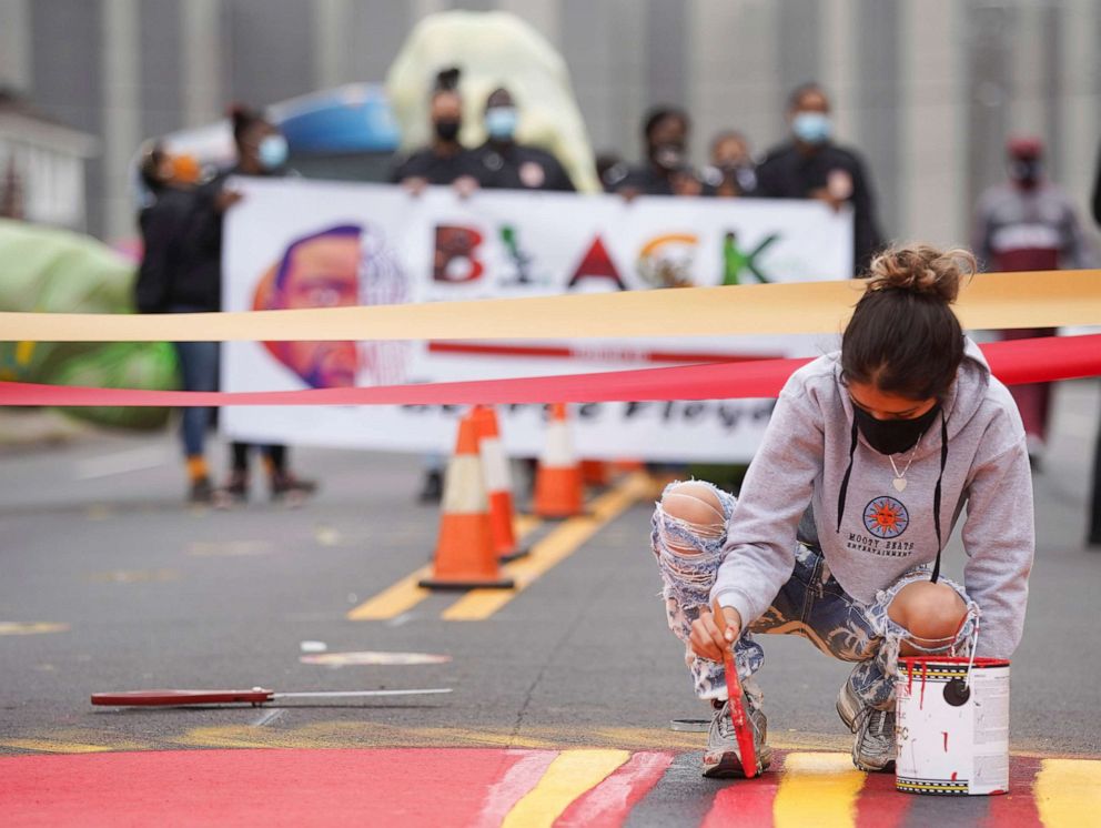 PHOTO: Brittany Torres works on a mural in honor of Black History Month and George Floyd in front of HISD's Jack Yates High School, Floyd's alma mater, in Houston, Texas, Feb. 6, 2021.