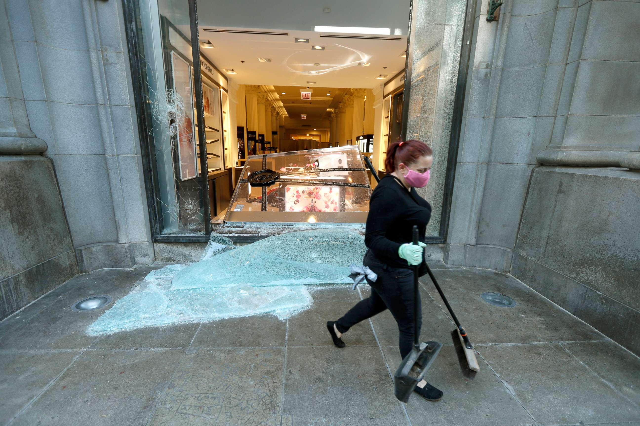 PHOTO: A volunteer worker walks past a shattered display window early, May 31, 2020, at the downtown Macy's store in Chicago, after a night of unrest and protests over the death of George Floyd, a black man who was in police custody in Minneapolis.