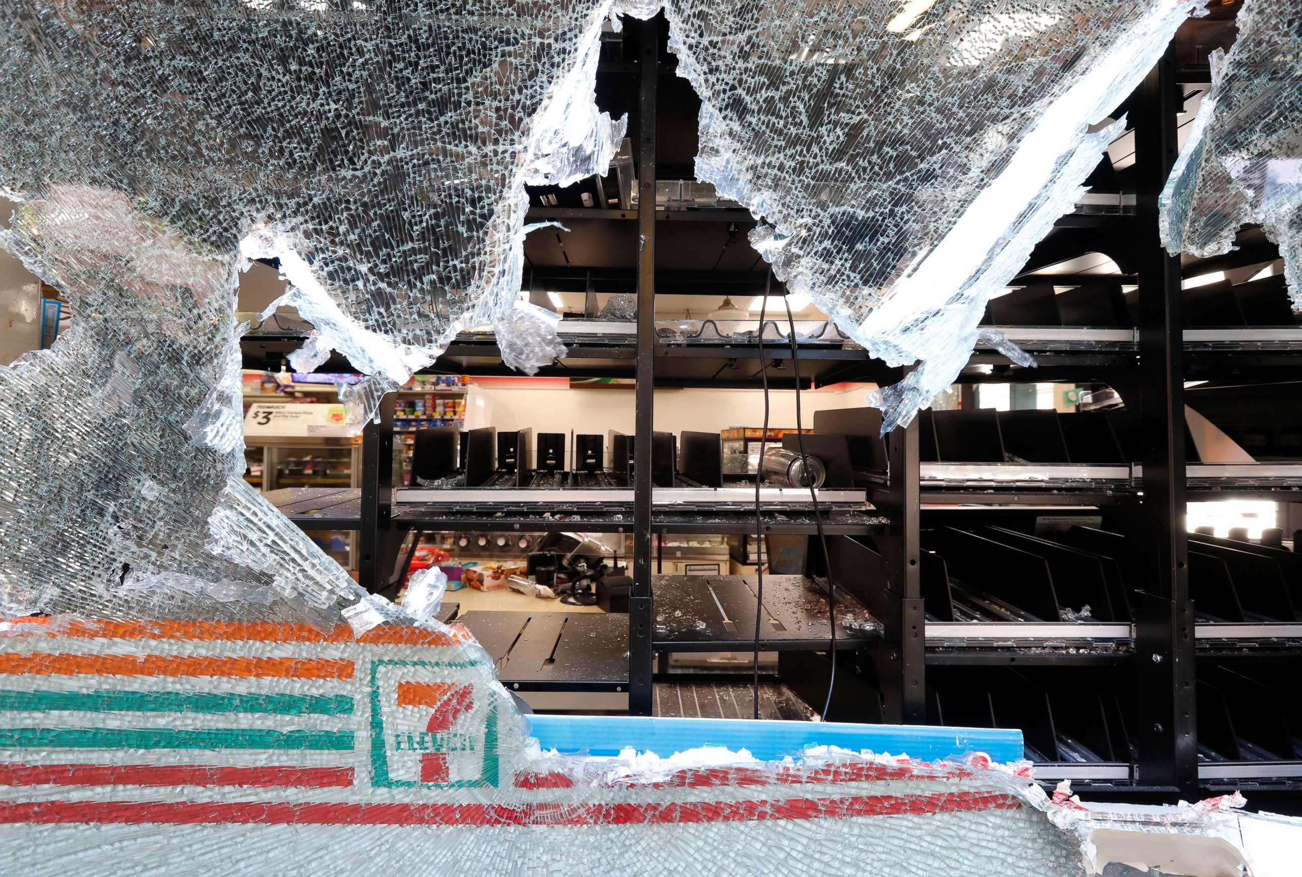 PHOTO: Shattered glass hangs from a window of a 7-Eleven store early, May 31, 2020, in Chicago, after a night of unrest and protests over the death of George Floyd, a black man who was in police custody in Minneapolis.