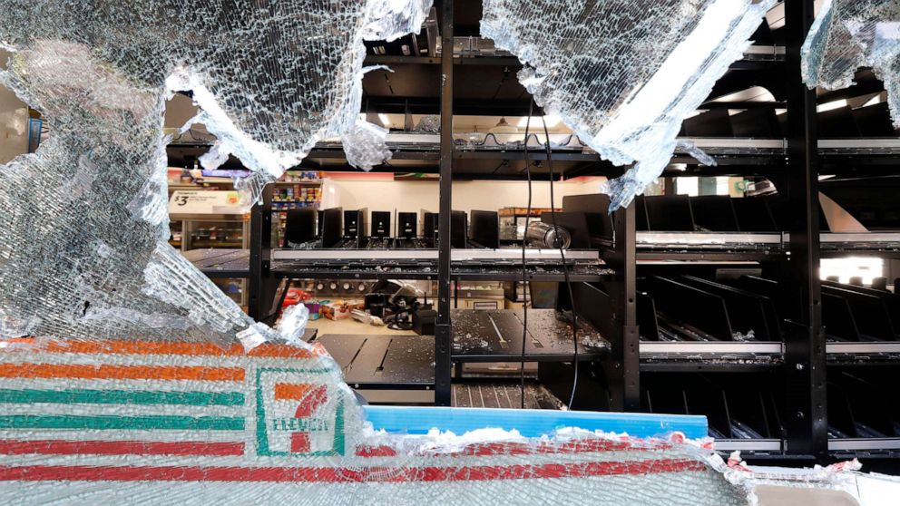 PHOTO: Shattered glass hangs from a window of a 7-Eleven store early, May 31, 2020, in Chicago, after a night of unrest and protests over the death of George Floyd, a black man who was in police custody in Minneapolis.