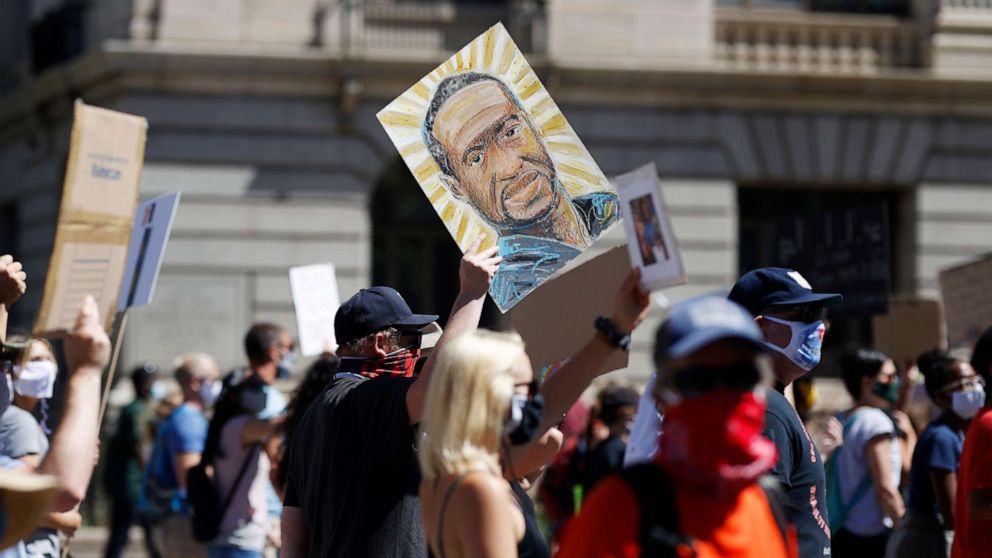 PHOTO: A placard with a portrait of George Floyd is held above demonstrators as they march calling for more oversight of the police, June 7, 2020, in Denver.
