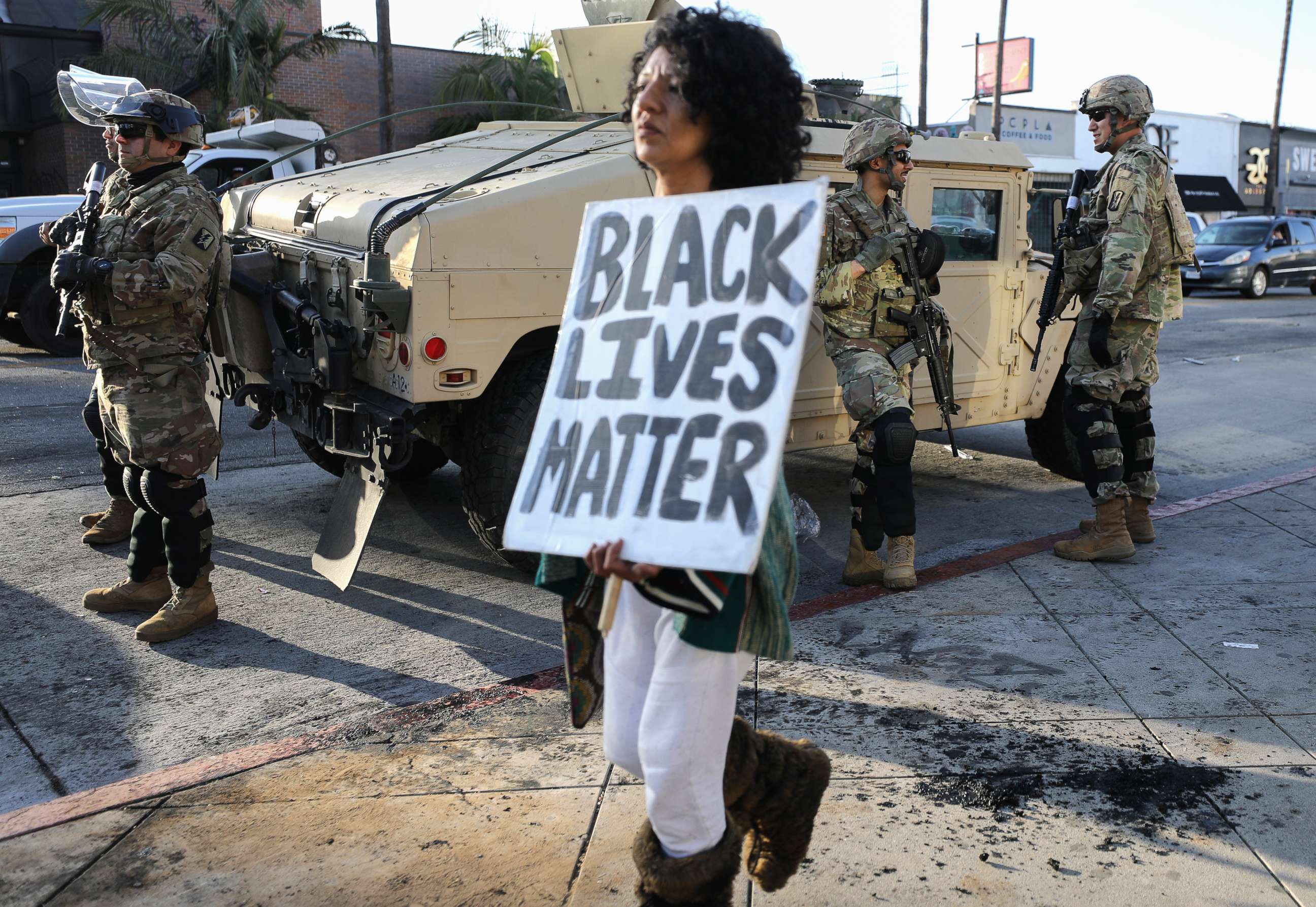 PHOTO: A woman carries a 'Black Lives Matter' sign past U.S. National Guard troops, May 31, 2020, in Los Angeles.