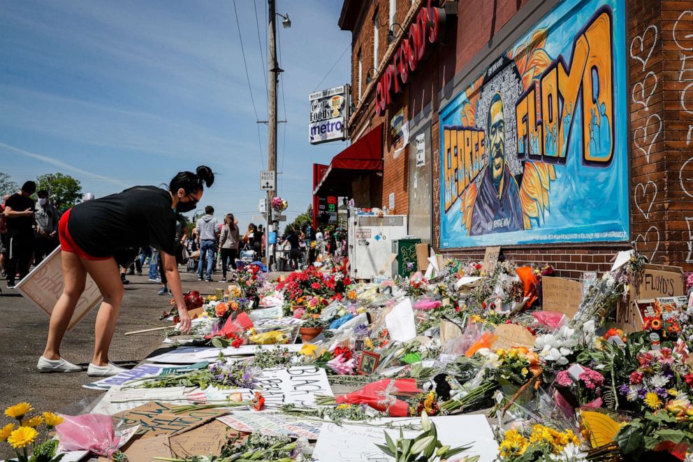 PHOTO: Jessica Knutson, and her daughter Abigail, 3, place flowers at a memorial to George Floyd, May 31, 2020, in Minneapolis. 