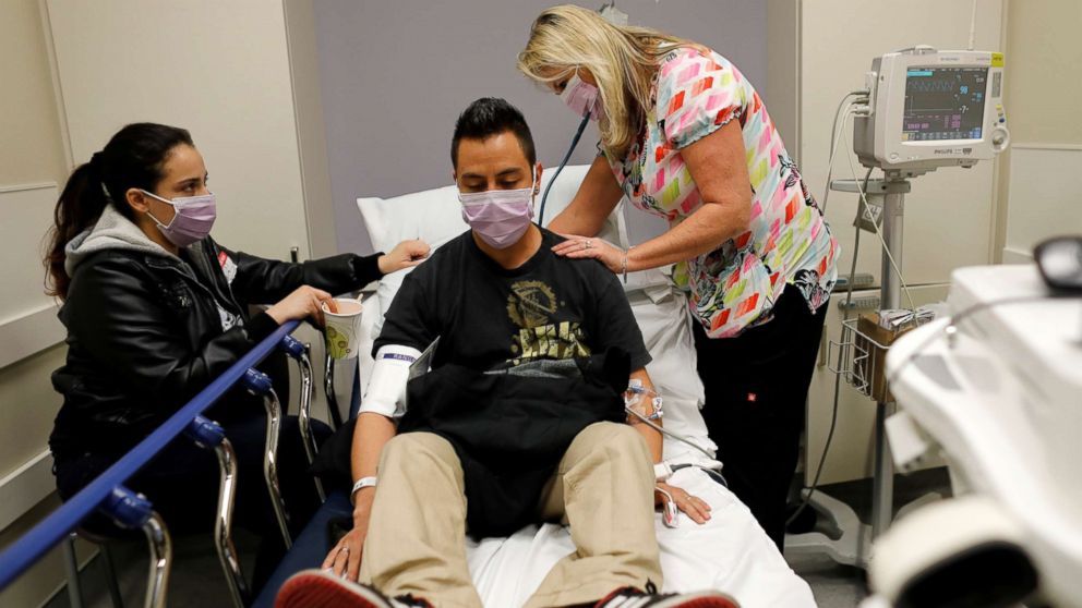 Emergency room nurse Christine Bauer treats a man from Vista, Calif., for the flu as his girlfriend looks on in the emergency room at Palomar Medical Center in Escondido, Calif., Jan. 18, 2018.