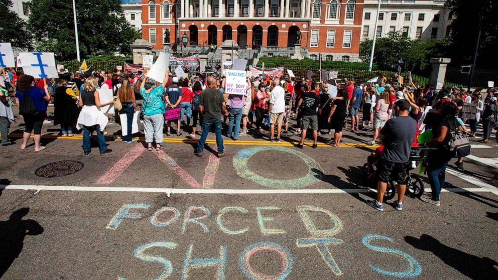 PHOTO: People draw a "No Forced Shots" message on the street in chalk  during a protest after a mandate requiring all children,age K-12, to receive an influenza (flu) vaccine/shot to attend school in Boston on August 30, 2020. 