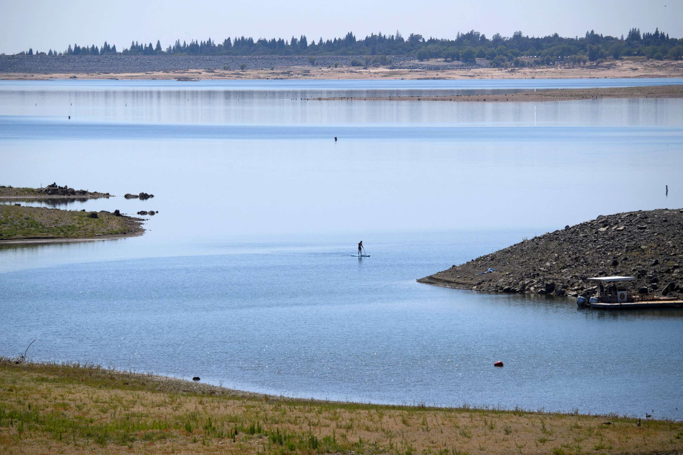 PHOTO: A paddle boarder paddles at Folsom Lake Marina as the lake experiences lower water levels during the California drought emergency, May 27, 2021, in El Dorado Hills, California.