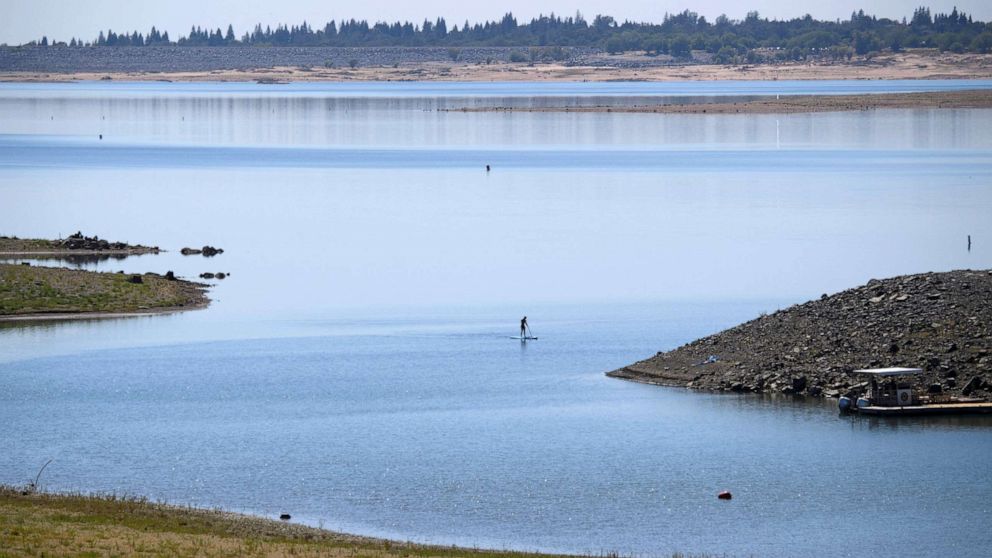 PHOTO: A paddle boarder paddles at Folsom Lake Marina as the lake experiences lower water levels during the California drought emergency, May 27, 2021, in El Dorado Hills, California.