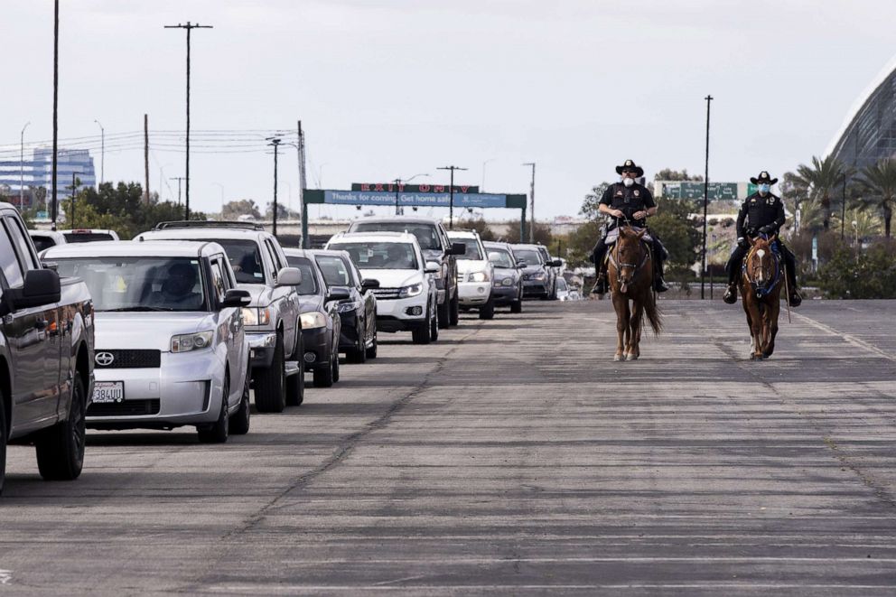 PHOTO: Anaheim police officers riding horses and wearing face masks monitor the traffic of people waiting in their cars during an Easter drive-thru food distribution at the Honda Center amid the coronavirus pandemic in Anaheim, Calif., April 11, 2020.