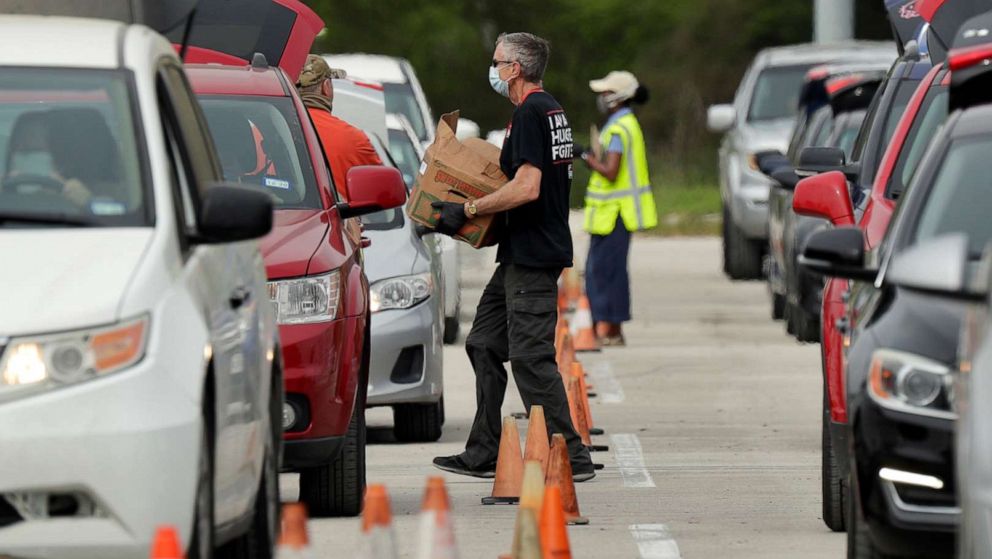 PHOTO: Workers and volunteers help load cars with food at a San Antonio Food Bank drive-through distribution in San Antonio, April 7, 2020. 