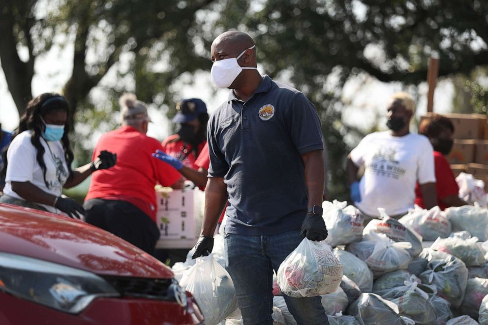 PHOTO: City of Opa-locka employees and volunteers place groceries provided by the food bank, Feeding South Florida, into vehicles of the needy at a drive-thru distribution site, April 14, 2020, in Opa-locka, Fla.