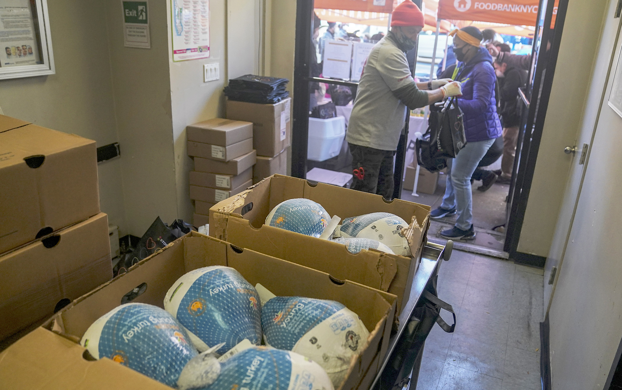 PHOTO:Volunteer Sean Armstrong, left, hands off bagged give away turkeys to volunteer Nina Norwood at Harlem's Food Bank For New York City, Nov. 16, 2020.