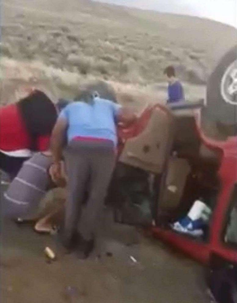 PHOTO: Members of the Boise Black Knights youth football team lift an overturned vehicle at they cut a woman out of her seat belt, May 30, 2018.