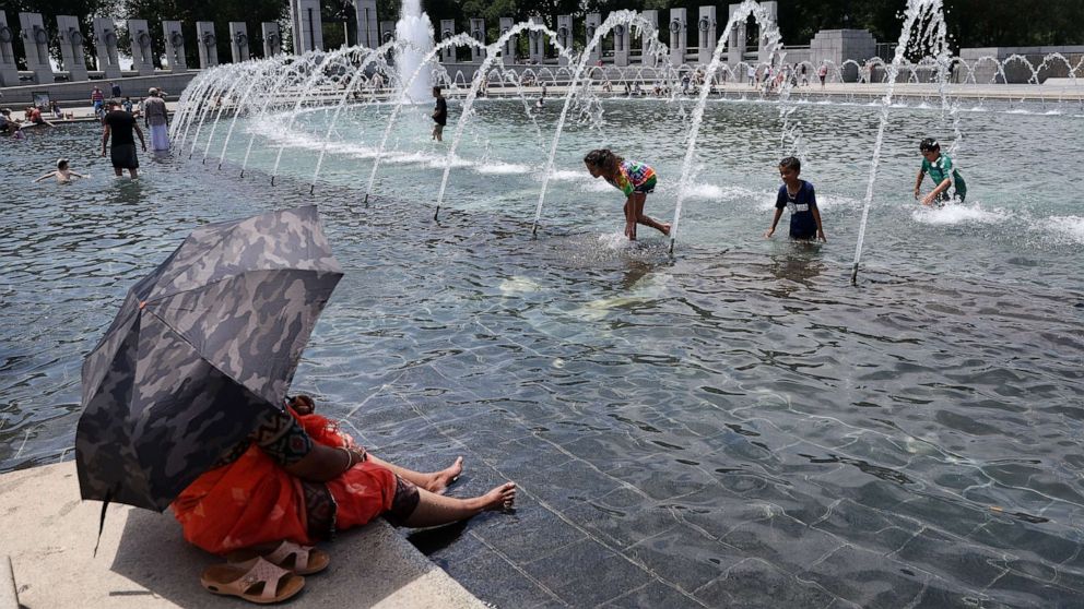 PHOTO: Visitors and tourists to the World War II Memorial seek relief from the hot weather in the memorial's fountain, July 3, 2023 in Washington, D.C.