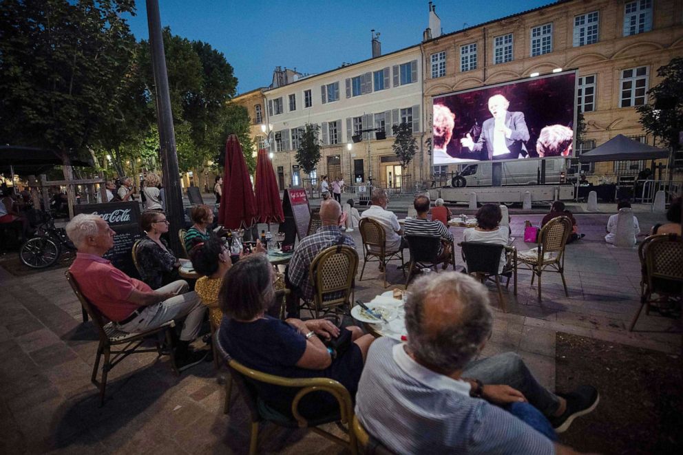PHOTO: People look at a video projection of a concert, recorded by the Baltasar Neumann Orchestra at the Cours Mirabeau plaza in Aix-en-Provence on July 21, 2020.