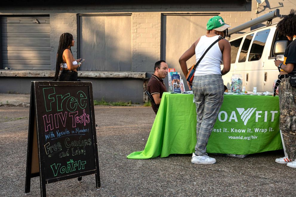 PHOTO: People gather at an information table before signing up for their free HIV tests in an outdoor event celebrating PRIDE month, encouraging COVID-19 vaccination and offering free HIV tests in Louisville, Kentucky, June 4, 2021.