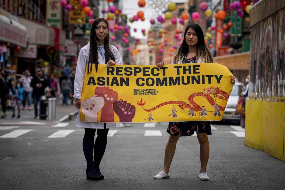 PHOTO: Dr. Michelle Lee, left, a radiology resident, and Ida Chen, right, a physician assistant student, unfold a banner Lee created to display at rallies protesting anti-Asian hate in the Chinatown area of New York, April 24, 2021.