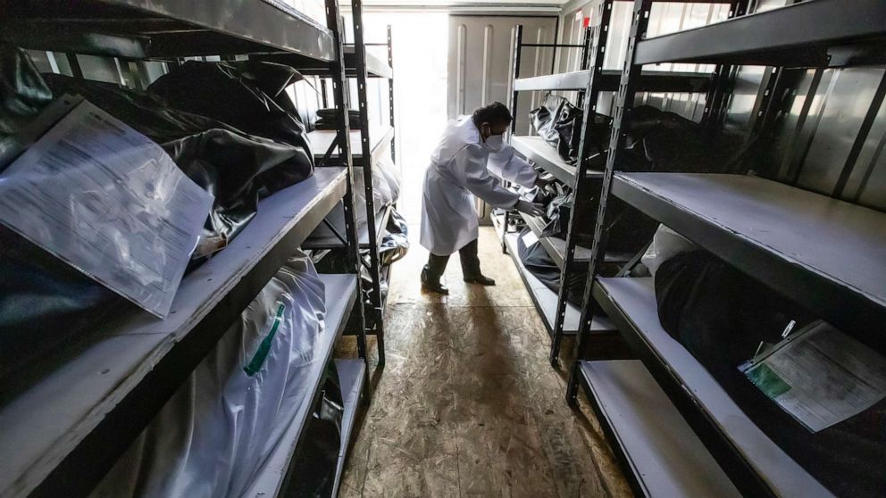 PHOTO: A funeral home driver handles one of the Covid-19 victims held stored in a mobile refrigerator outside the facility in Los Angeles, Aug. 21, 2020.