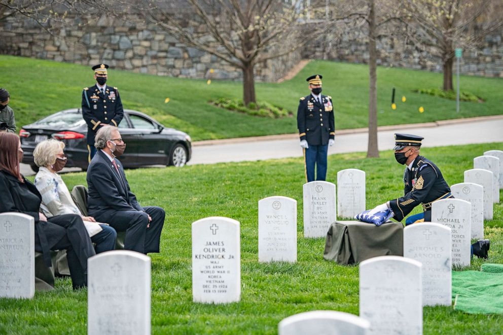 PHOTO: A soldier assigned to 1st Battalion, 3d U.S. Infantry Regiment presents the U.S. flag to Robert Belch (third from left seated) during the funeral of his father at Arlington National Cemetery, Arlington, Va., April 14, 2020.