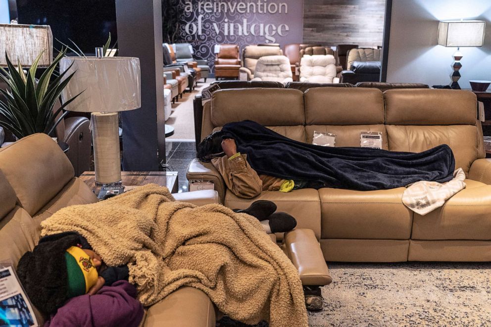 PHOTO: People sleep on couches while taking shelter at Gallery Furniture store which opened its door and became a temporary warming station after winter weather caused electricity blackouts on Feb. 18, 2021, in Houston.