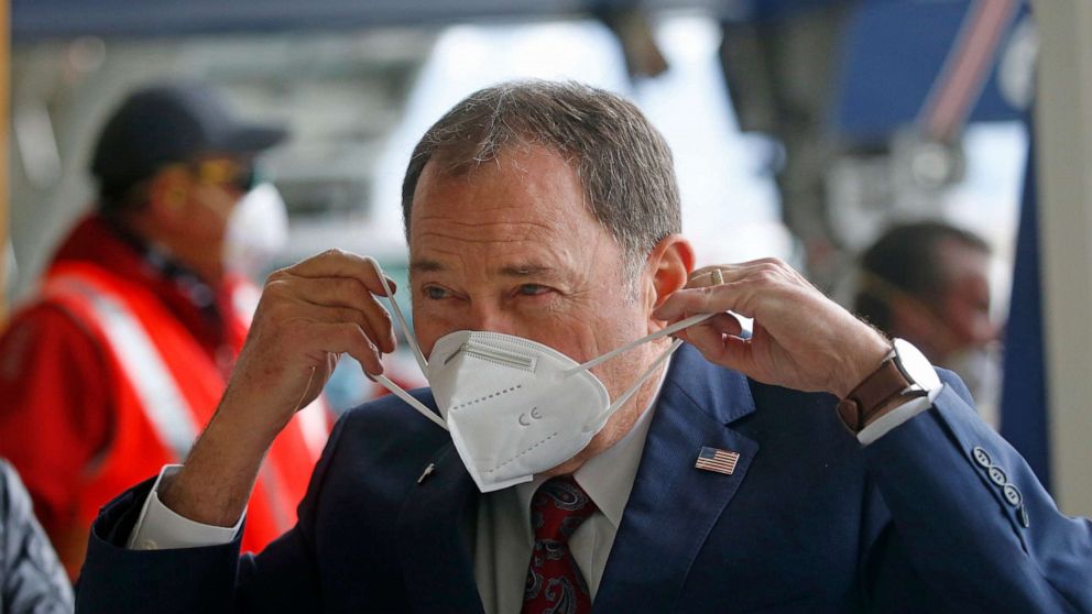 PHOTO: Utah Gov. Gary Herbert puts on a mask that came off a plane filled with personal protective equipment at the Delta Hanger Wednesday, April 15, 2020, at the Salt Lake International Airport.